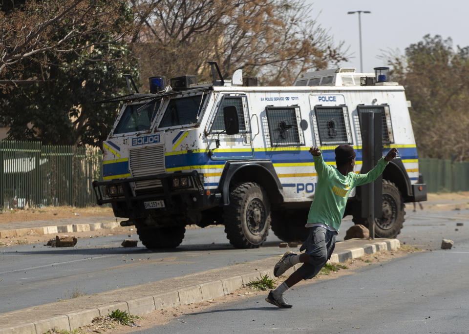 Protesters run for cover as they clash with police in Eldorado Park, Johannesburg, South Africa, Thursday, Aug. 27, 2020. Residents from the township, south of Johannesburg are demanding justice for a teenager shot and killed, allegedly at the hands of police Wednesday. (AP Photo/Themba Hadebe)