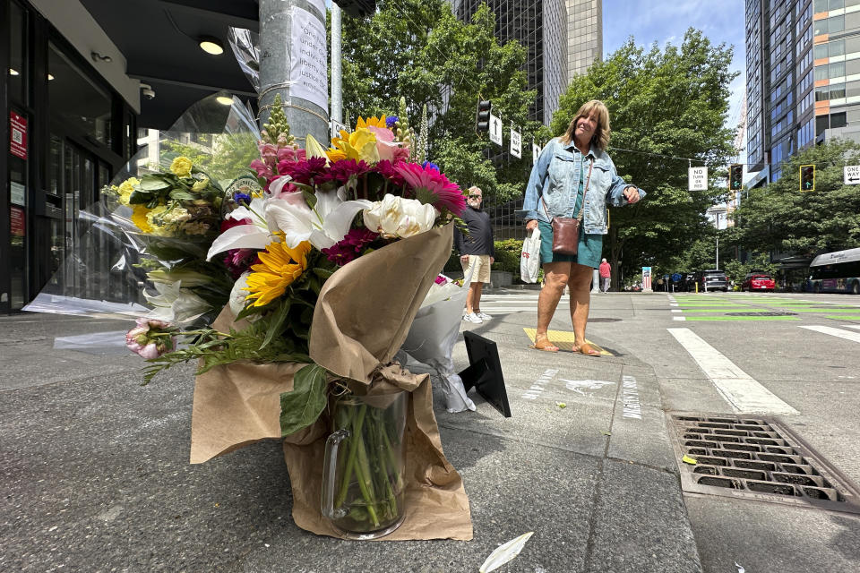 An onlooker reads signs posted on a memorial for Eina Kwon in Seattle on Friday, June 16, 2023. Kwon was killed in what appears to have been a random shooting in downtown Seattle this week near the city's famed Pike Place Market. (AP Photo/Manuel Valdes)