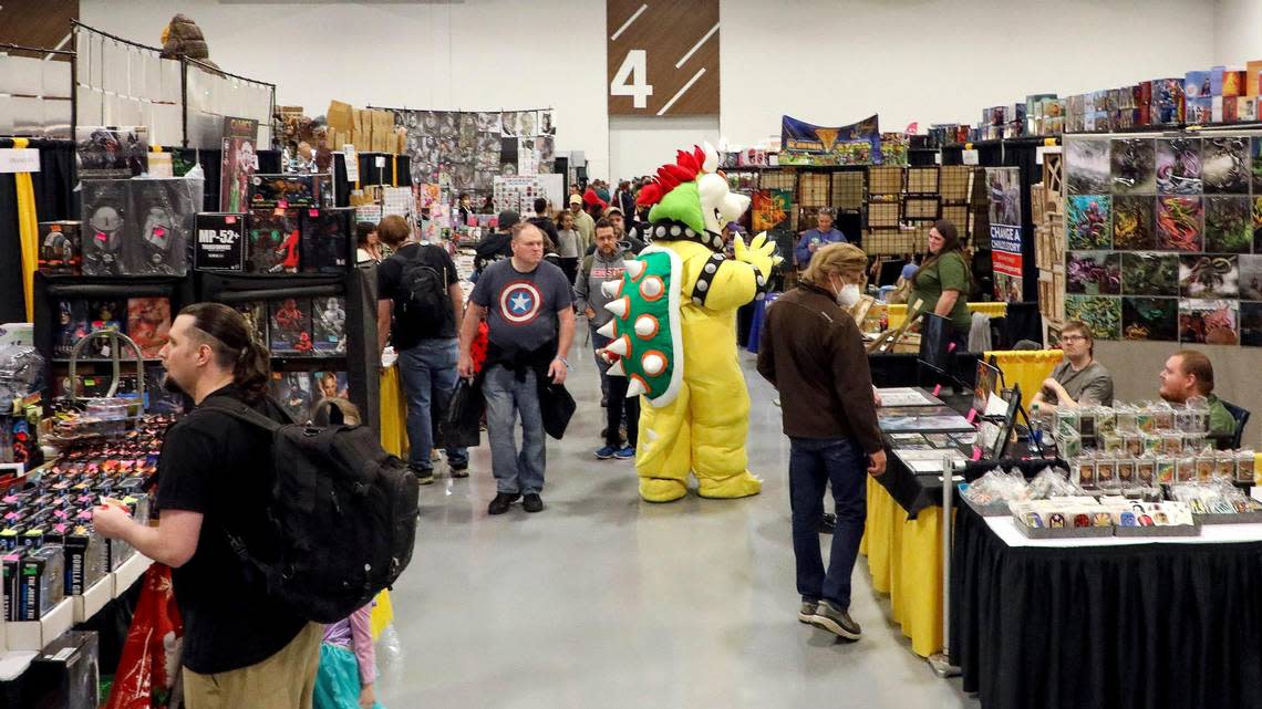 Patrons, including someone dressed up in cosplay as Bowser from Super Mario Bros., wander the exhibit floor during the 2022 Lexington Comic and Toy Convention at the Central Bank Center in Lexington, Ky. on Sunday, March 27, 2022. Vendors were selling rare toys and collectibles, comics, art work and pop culture goods from their booths.