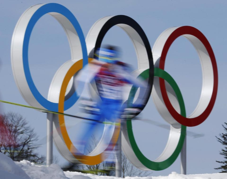 In this photo taken with slow shutter speed athletes pass by the Olympic rings during the men's 50K cross-country race at the 2014 Winter Olympics, Sunday, Feb. 23, 2014, in Krasnaya Polyana, Russia. (AP Photo/Dmitry Lovetsky)