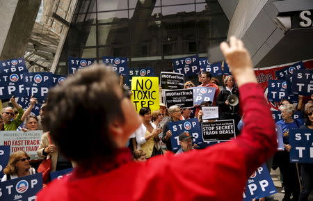 A woman snaps a photograph of a group of demonstrators who were protesting the Trans-Pacific Partnership, at the Federal Buileing in San Francisco, California June 9, 2015. REUTERS/Robert Galbraith