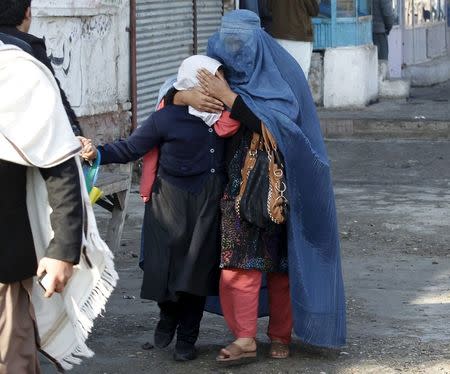 A woman holds her daughter's head as they walk away after a blast near the Pakistani consulate in Jalalabad, Afghanistan January 13, 2016. REUTERS/Parwiz