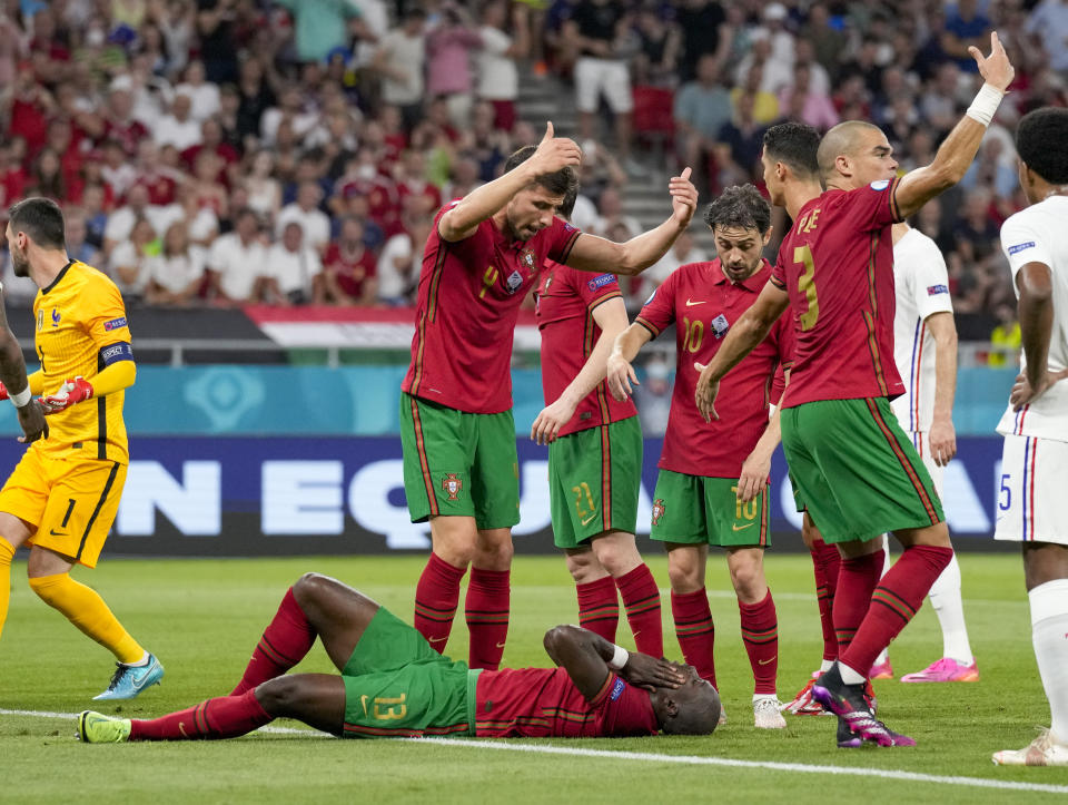 Portugal's Danilo Pereira lies on the pitch after a collision with France's goalkeeper Hugo Lloris, left, during the Euro 2020 soccer championship group F match between Portugal and France at the Puskas Arena, Budapest, Hungary, Wednesday, June 23, 2021. (AP Photo/Darko Bandic,Pool)