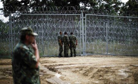 Bulgarian military personnel inspect a barbed wire fence constructed on the Bulgarian-Turkish border July 17, 2014. REUTERS/Stoyan Nenov