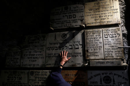 A man touches a gravestone commemorating the Jewish villages and towns whose communities were wiped out by the Nazis, inside "The Chamber of the Holocaust", a little-known memorial site for Jewish victims of the Nazi Holocaust, in Jerusalem's Mount Zion January 23, 2019. REUTERS/Ronen Zvulun