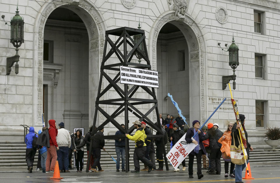 FILE - In this Feb. 6, 2015, file photo, protesters prepare to take down a makeshift oil derrick that was set up in front of the California State Office Building to protest fracking in San Francisco. On Friday, April 23, 2021, California Gov. Gavin Newsom announced he would halt all new fracking permits in the state by January 2024. He also ordered state regulators to plan for halting all oil extraction in the state by 2045. (AP Photo/Jeff Chiu, File)