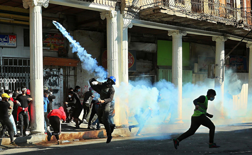 An anti-government protester prepares to throw back a tear gas canister fired by police during clashes in Baghdad, Iraq, Nov. 22, 2019. (Photo: Hadi Mizban/AP)