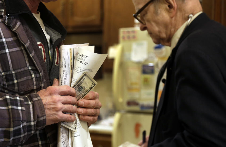 In this Tuesday, Oct. 30, 2012 photo, patient Joe Logsdon holds $5 in his hand to pay for his office visit as Dr. Russell Dohner, right, walks past in Rushville, Ill. When Dohner started practicing medicine in Rushville in 1955, he charged $2, the going rate around town for an office visit but has since raised it to $5. (AP Photo/Jeff Roberson)