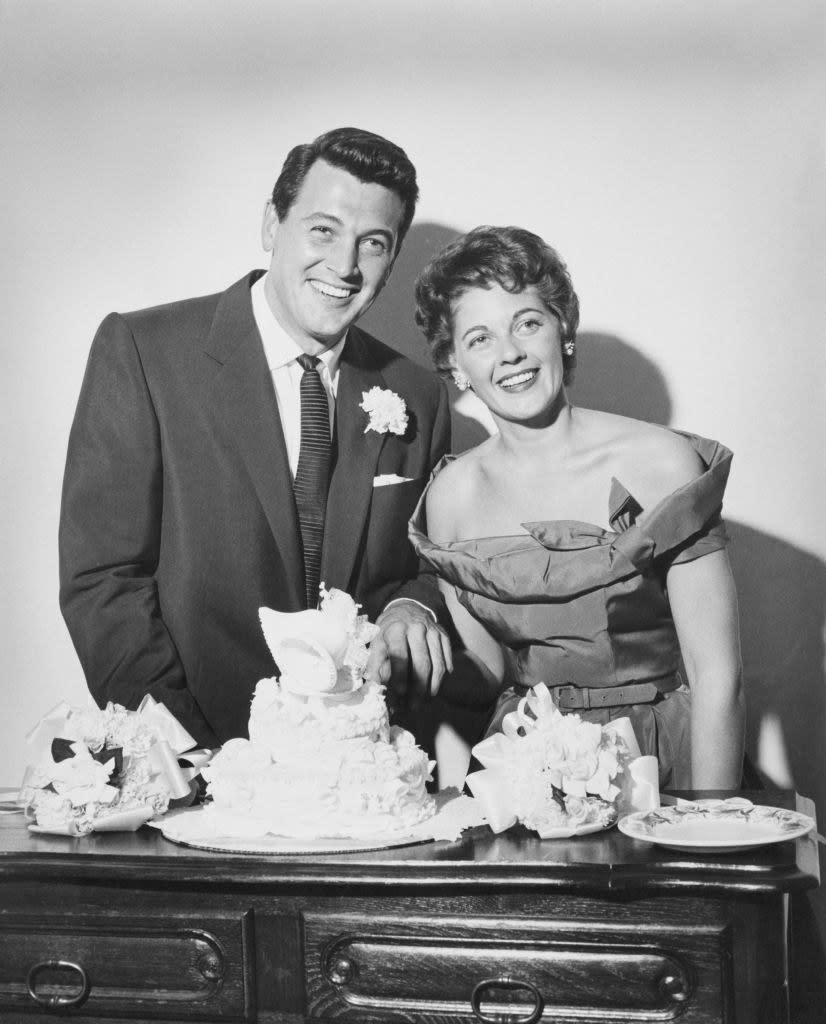 Rock and Phyllis smiling in front of a wedding cake