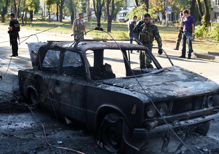 A pro-Russian militant speaks on the phone as he secures the area around a burnt car in downtown Donetsk, eastern Ukraine on August 27, 2014