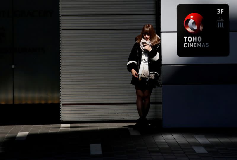 FILE PHOTO: A woman stands next to the logo of Toho Cinemas at its multiplex in Tokyo