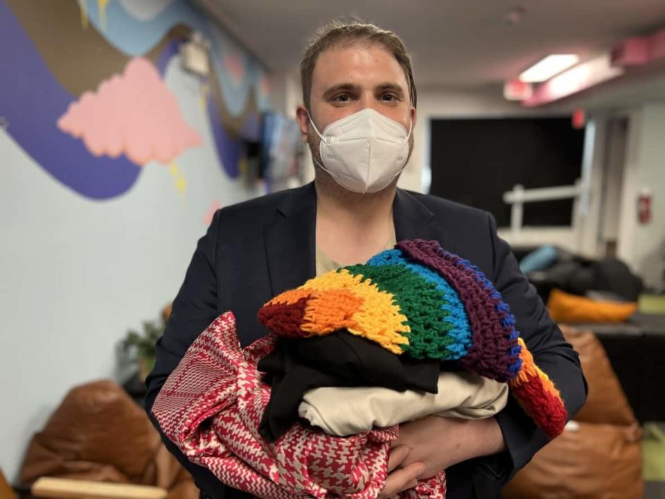 Samuel Braemer, co-founder of Transforming Style, holds items donated to the non-profit organization during an event at OutSaskatoon on March 11, 2022.  (Don Somers/CBC - image credit)