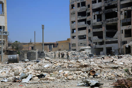 Forces loyal to Syria's President Bashar al-Assad walk past damaged buidlings after they advanced on the southern side of the Castello road in Aleppo, Syria, in this handout picture provided by SANA on July 28, 2016. SANA/Handout via REUTERS