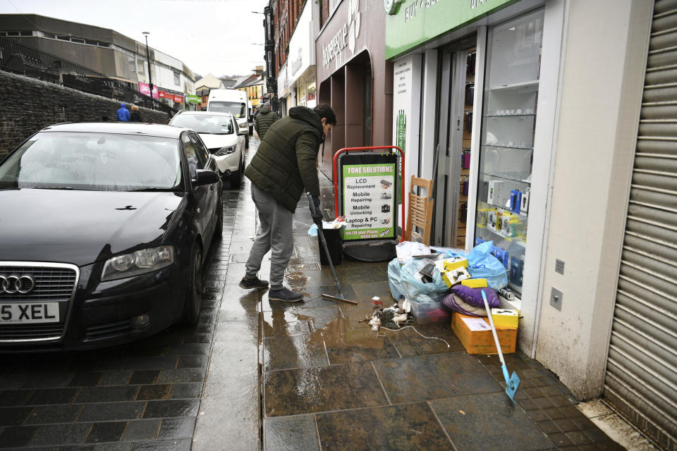 A man cleans up outside his shop, after Storm Dennis hits the UK leading to widespread flooding, in Pontypridd, Wales, Sunday, Feb. 16, 2020. Storm Dennis roared across Britain with high winds and heavy rains Sunday, prompting authorities to issue some 350 flood warnings, including a “red warning" alert for life-threatening flooding in south Wales. (Ben Birchall/PA via AP)
