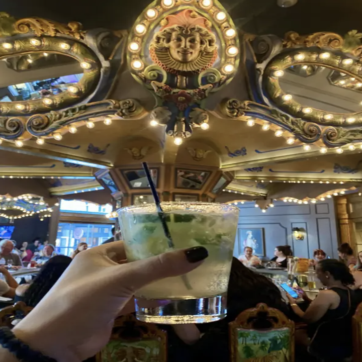 a former buzzfeeder holding up a drink at Carousel Bar