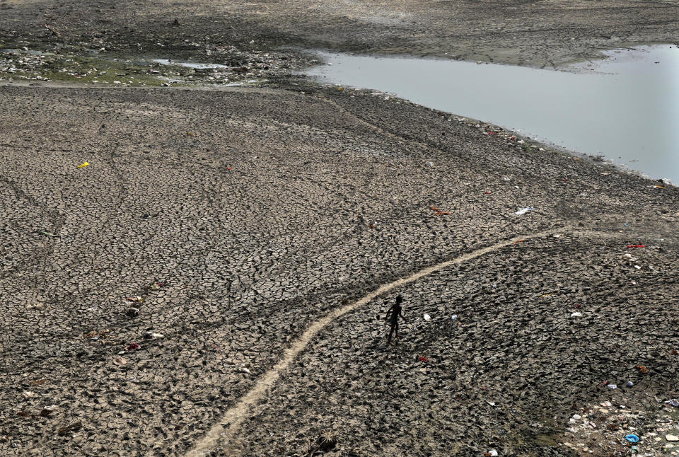 FILE - A man walks across a dried patch of the river Yamuna as water level reduces drastically following heat wave to in New Delhi, May 2, 2022. Loss and damage is the human side of a contentious issue that will likely dominate climate negotiations in Egypt. In India, it's record heat connected to climate change that caused deaths and ruined crops. (AP Photo/Manish Swarup, File)