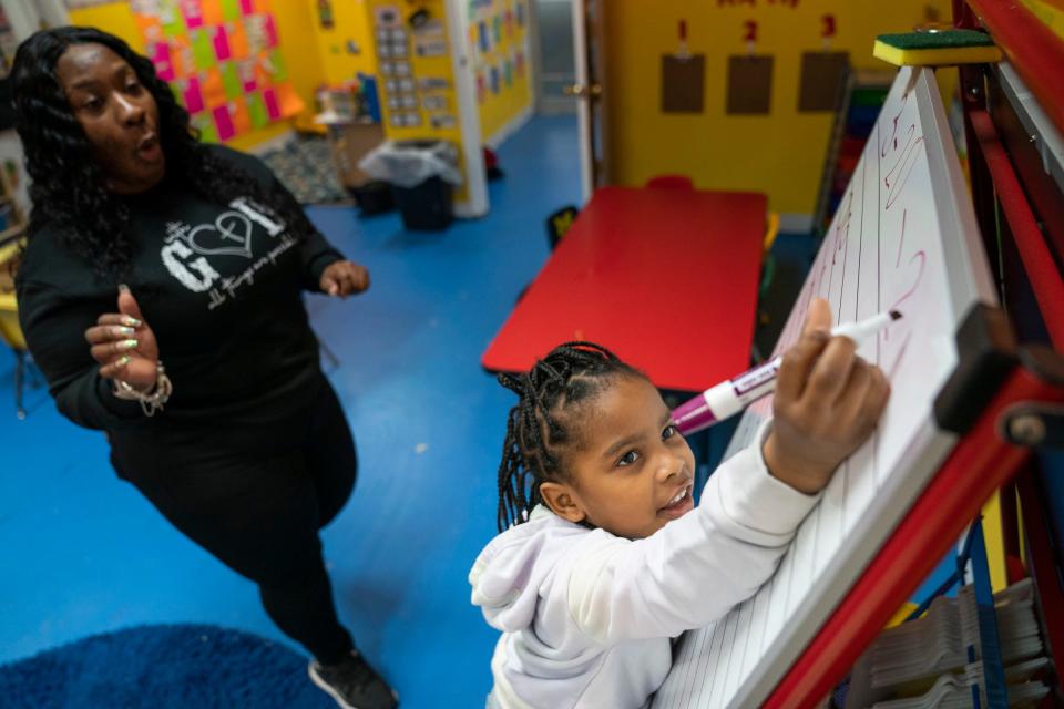 School of Purpose director and teacher Sherri Robinson, 41, left, helps her daughter Bailee Robinson, 5, remember the date that gets filled out every day on a worksheet at the school in Detroit on Wednesday, March 20, 2024.