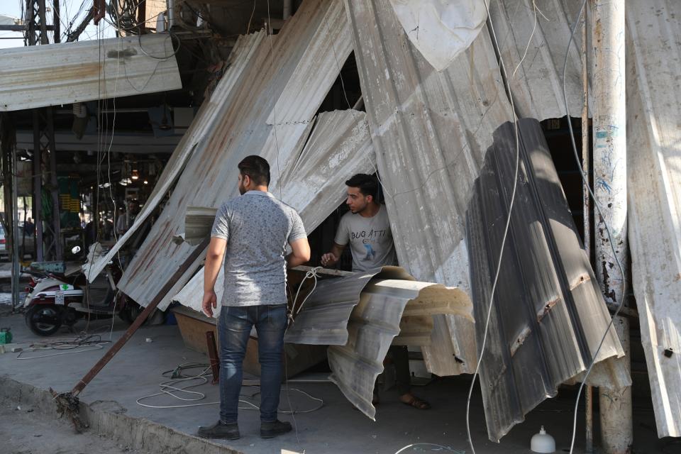 Shop owners survey the damage to their shops a day after a motorcycle rigged with explosives blew up in Mussayyib, south of Baghdad, Iraq, Saturday, Aug. 29, 2019. The officials said Saturday that the blast occurred the previous evening on a commercial street in the village of Mussayyib, killing and wounding civilians. (AP Photo/Khalid Mohammed)