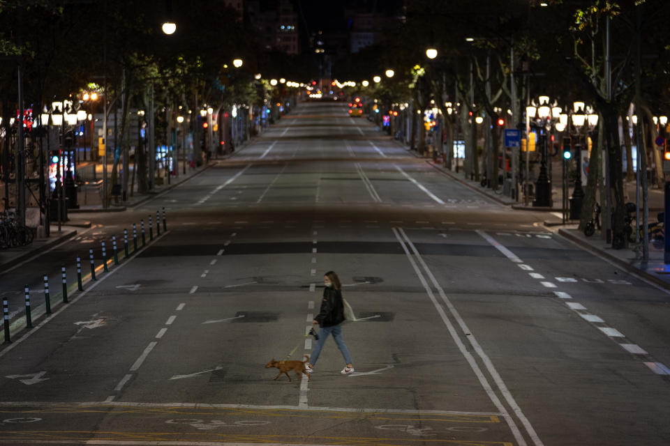 A resident walks with a dog on an empty street after curfew in Barcelona on Oct. 25, 2020. Spain imposed the curfew to stem a worsening COVID-19 outbreak.  / Credit: Emilio Morenatti / AP