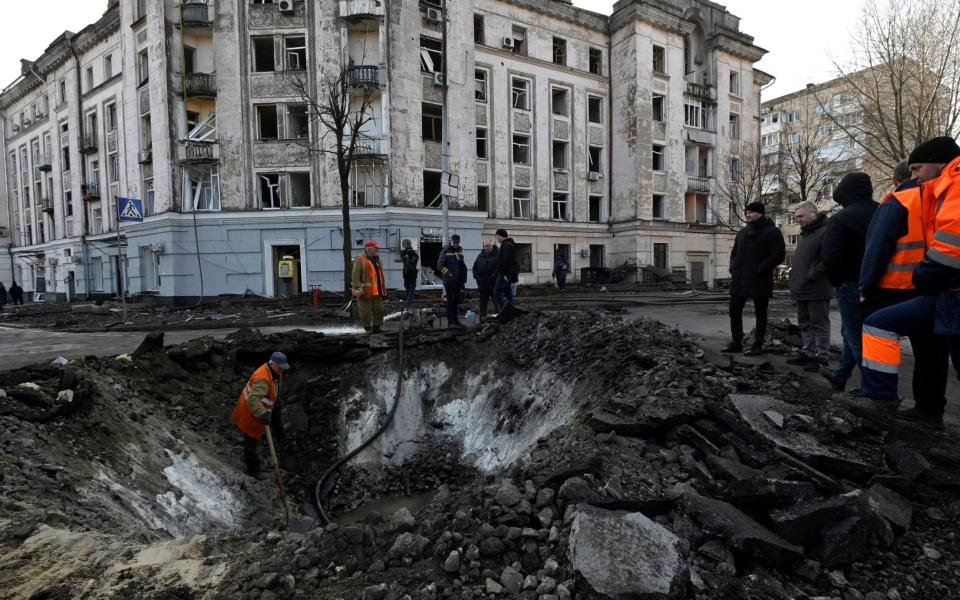 Ukrainian municipal services workers survey and repair the damage following a missile attack in Kyiv