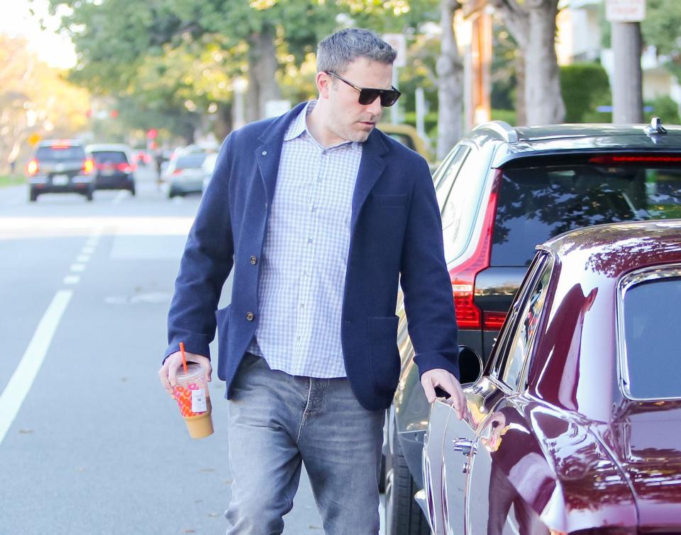 A closeup of Ben walking outside with coffee