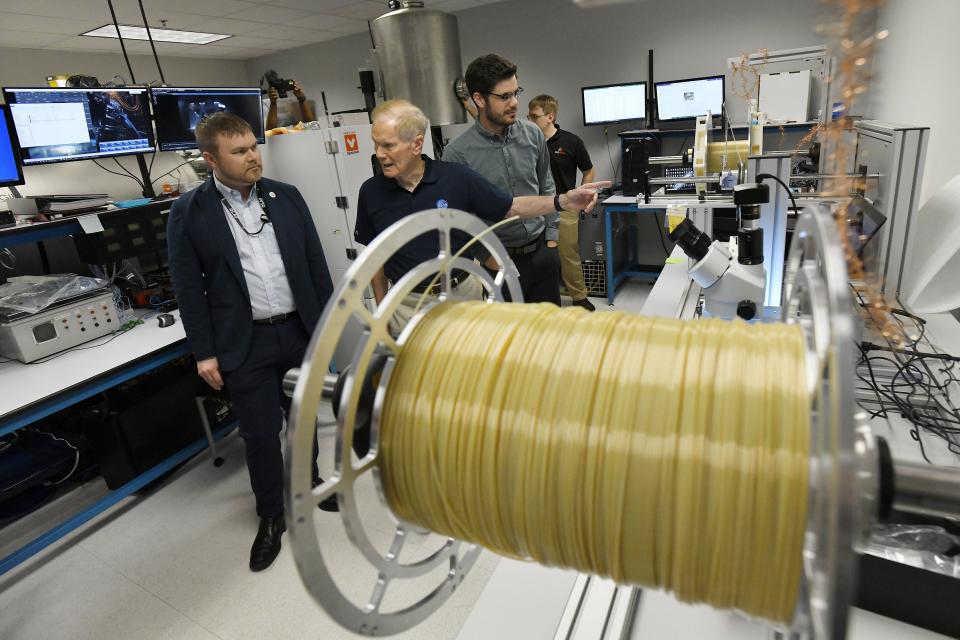 Justin Kugler, the general manager of the Jacksonville Redwire facility talks with NASA Administrator Bill Nelson as they look over a device creating spools of Ultem plastic that will be used to print 50-foot support beams in space on Redwire's Archinaut self-constructing satellite in the lab overseen by Material Scientist Benjamin Stubbs during Nelson's tour of the facility May 10 in Jacksonville.