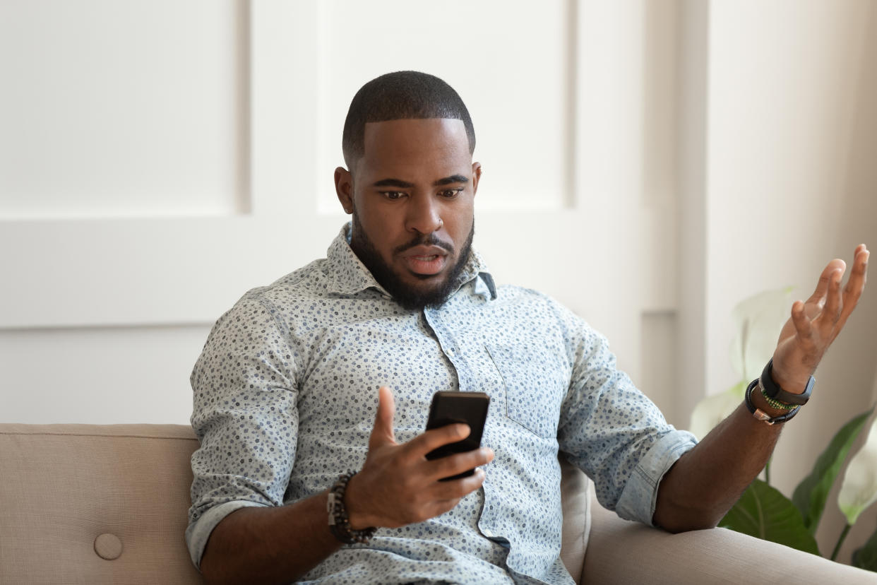 Man sitting on sofa holds cellphone read e-mail sms feels shocked received terrified news, guy looks at online calendar forgot missed important meeting, phone crash problems concept