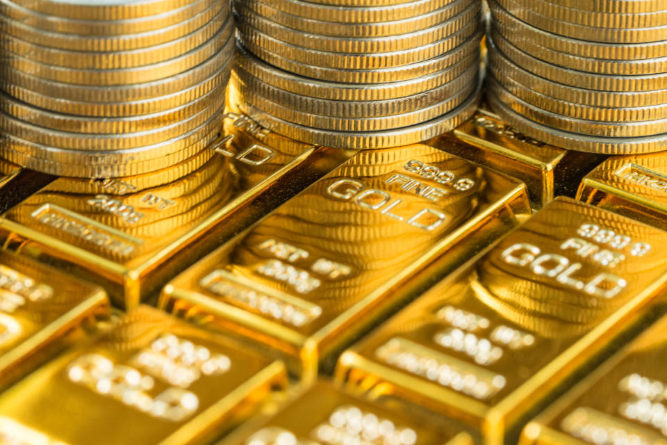 Stacks of gold coins sit on rows of gold bars.