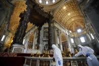 Workers in protective gear sanitize beneath the baroque sculpted bronze canopy of St. Peter's Baldachin inside St. Peter's Basilica, at the Vatican, Friday, May 15, 2020. Churches in Italy are preparing to reopen to the public for masses from May 18 after Italy partially lifted restrictions last week following a two-month lockdown due to COVID-19. (AP Photo/Andrew Medichini)