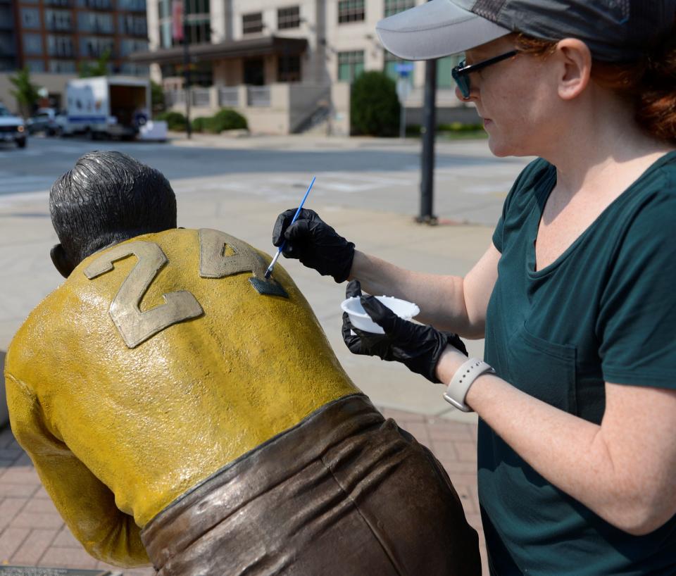 Jessica LoPresti of Sculpture Resource in Highland Park, Illinois, paints a blue number on the Johnny Blood statue in Packers Heritage Plaza in downtown Green Bay on Sept. 14, 2022.