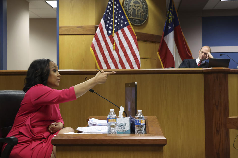 Fulton County District Attorney Fani Willis gestures while testifying as Fulton County Superior Judge Scott McAfee presides during a hearing on the Georgia election interference case, Thursday, Feb. 15, 2024, in Atlanta. The hearing is to determine whether Willis should be removed from the case because of a relationship with Nathan Wade, special prosecutor she hired in the election interference case against former President Donald Trump. (Alyssa Pointer/Pool Photo via AP)
