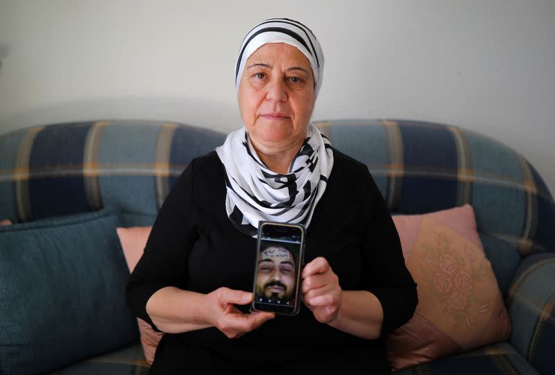 Syrian immigrant Hallak holds a phone with a picture of her dead son Ayham in Berlin