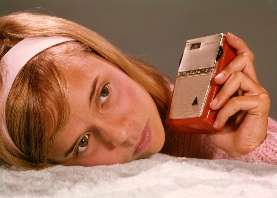 A little girl listening to a transistor radio