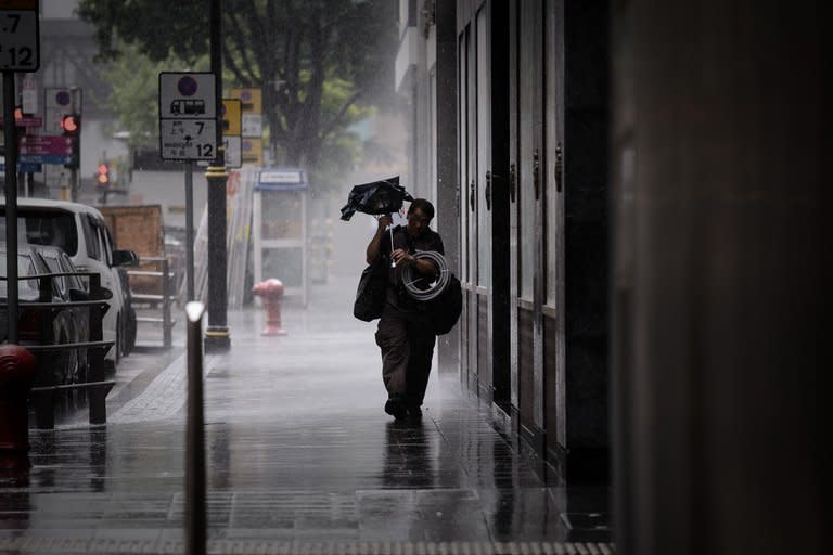 A man battles with his broken umbrella against heavy winds in Hong Kong on August 13, 2013. Hong Kong battened down Wednesday as Severe Typhoon Utor forced the closure of the financial market and disrupted hundreds of flights