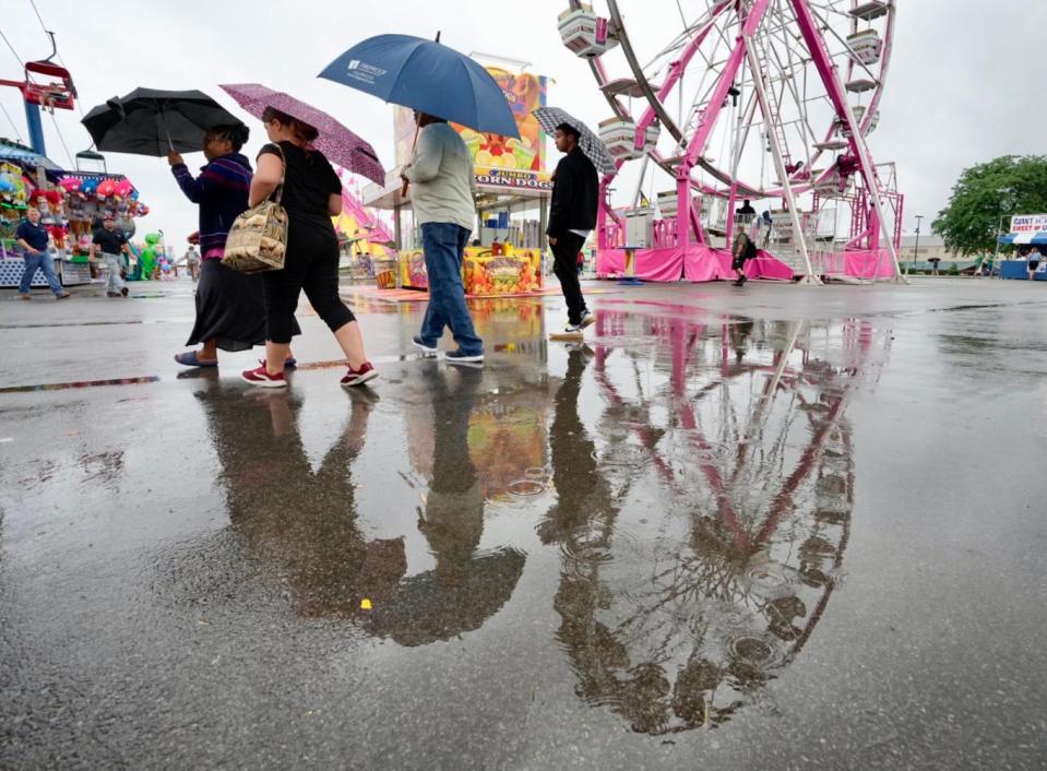 Visitors walk past rides during a slight drizzle on the opening day of the Ohio State Fair. There is a chance of more rain on Thursday and Friday.