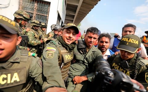 Colombian police escorting a Venezuelan soldier who surrendered at the Simon Bolivar international bridge - Credit: AP
