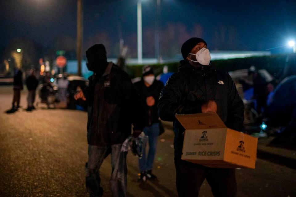 Volunteers hand out food and supplies to people living unhoused along East I Street in Tacoma, Wash., on Thursday, Jan. 27, 2022.