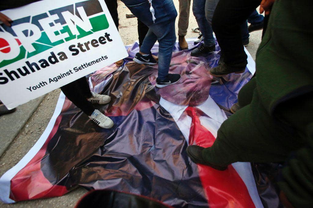 Palestinian demonstrators stand on a poster of US President Donald Trump as they protest against his support of Israel and demand for the Israeli army to re-open Shuhada Street near a Jewish settlement in Hebron on 24 February, 2017: AFP/Getty Images