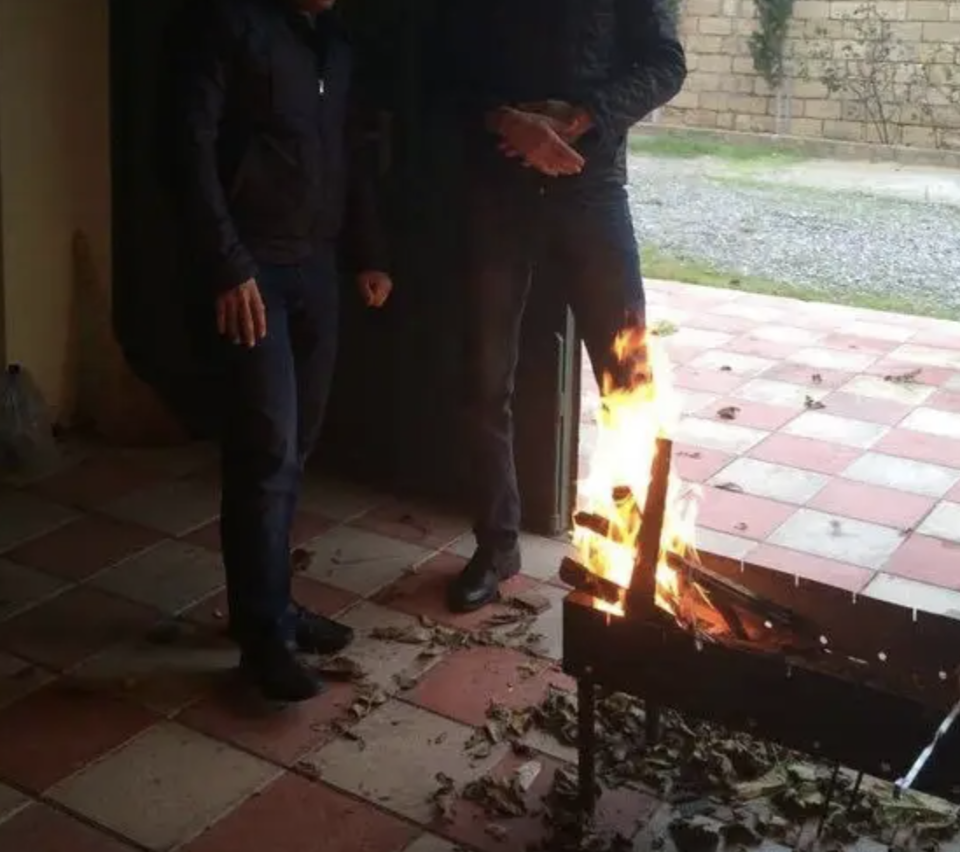 Two individuals standing by a flaming chessboard table outdoors