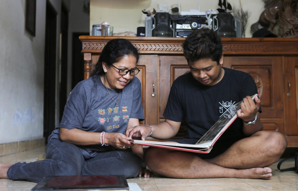 Ni Luh Erniati sits with her son, Made, going through family photo albums which show her late husband and his late father, Gede Badrawan, in Bali, Indonesia on Thursday, April 25, 2019. Gede was one of 202 people killed in the 2002 Bali bombings. After his death, the sight of Erniati's tears made Made cry, so she shut herself in the bathroom to weep alone. She spent years telling him that his father was simply away for work. He was 9 before she told him the truth. (AP Photo/Firdia Lisnawati)