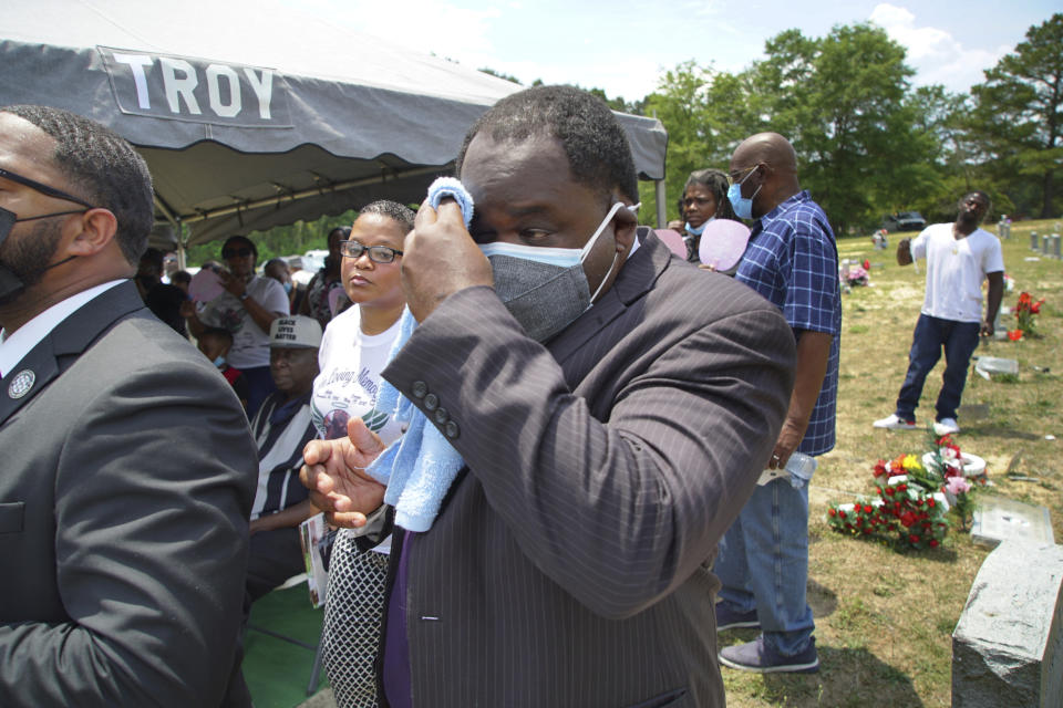 Funeral director Shawn Troy wipes away perspiration during a graveside service at Hillcrest Cemetery outside Mullins, S.C., on Monday, May 24, 2021. His father, William Penn Troy Sr., died of COVID-19 in August 2020, one of many Black morticians to succumb during the pandemic. (AP Photo/Allen G. Breed)