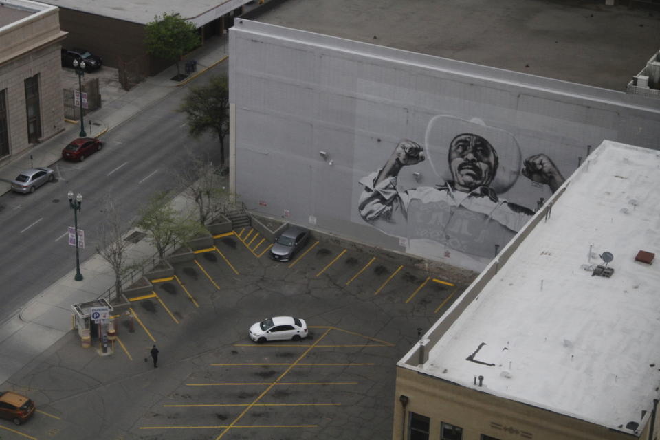 In this Wednesday, March 18, 2020 photo, a woman sweeps a nearly empty parking lot in downtown El Paso, Texas, as seen from the office building of Congresswoman Veronica Escobar, D-Texas. Traffic slowed in the city after sweeping measures to reduce the spread of COVID-19. After closing her office to in-person visits, Escobar held a virtual town hall for constituents to ask questions about government's response to the coronavirus. (AP Photo/Cedar Attanasio)