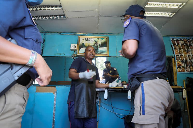 Metro Police officers order a barber to close his barbershop in Langa township, Cape Town