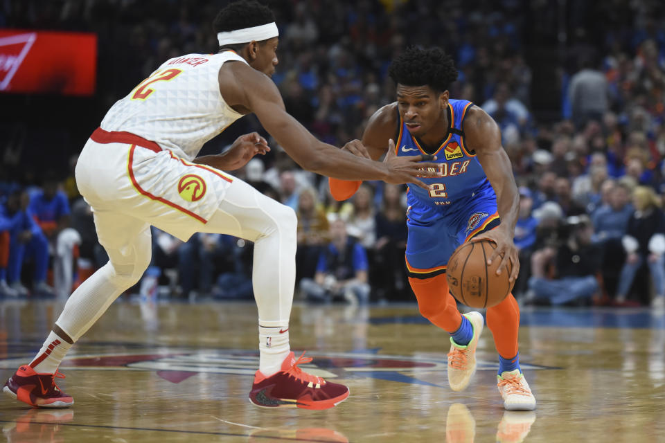 Oklahoma City Thunder guard Shia Gilgeous-Alexander (2) tries to push past Atlanta Hawks forward De'Andre Hunter (12) in the second half of an NBA basketball game, Friday, Jan. 24, 2020, in Oklahoma City. (AP Photo/Kyle Phillips)