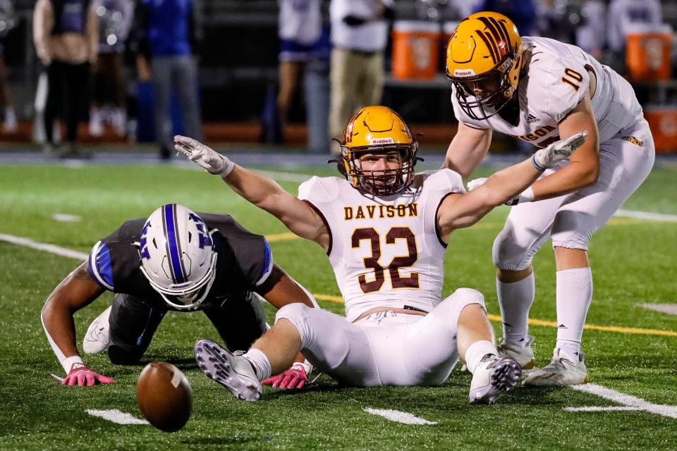 Davison outside linebacker Carter Herriman (32) celebrate a tackle against  Walled Lake Western running back Darius Taylor (1) during the first half at Walled Lake Western High School in Commerce Township on Friday, Sept. 30, 2022.