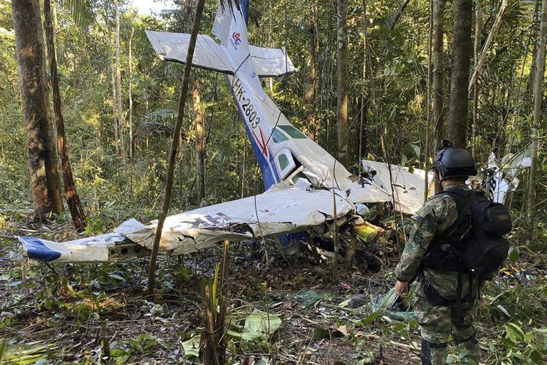 En esta foto proporcionada por la Oficina de Prensa de las Fuerzas Armadas de Colombia, un soldado permanece frente a los restos de una avioneta Cessna C206 el jueves 18 de mayo de 2023; en esa avioneta viajaban los niños