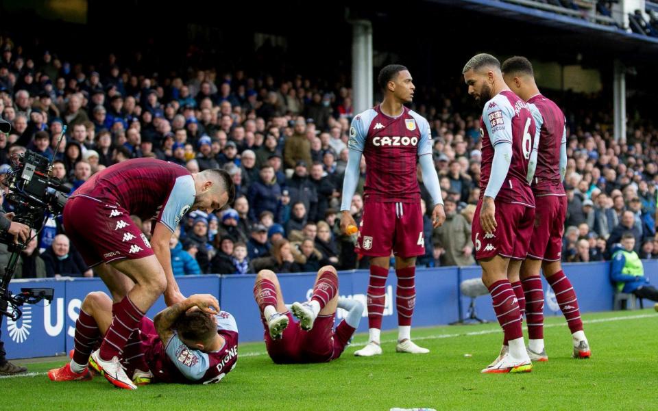 Matty Cash and Lucas Digne of Aston Villa on the ground after being struck by objects thrown at them during celebrations for Emi Buendia's goal during the Premier League match between Everton and Aston Villa at Goodison Park on January 22, 2022 in Liverpool, England - Neville Williams/Aston Villa FC via Getty Images