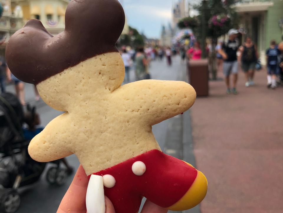 hand holding a mickey-shaped sugar cookie at disney world