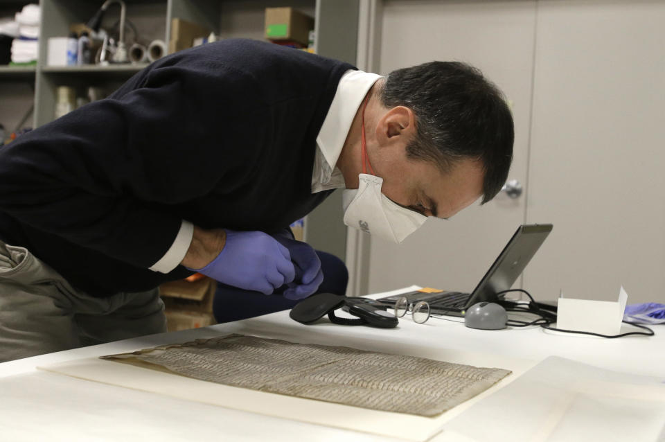 In this Wednesday, Feb. 5, 2014 photo, wearing special gloves and a mask, Chris Woods, director of London's National Conservation Service, inspects the Magna Carta, after its arrival in Houston. The centuries old parchment, which has never left England before, will be on display at the Houston Museum of Natural Science for six months starting Feb. 14, 2014. (AP Photo/Pat Sullivan)