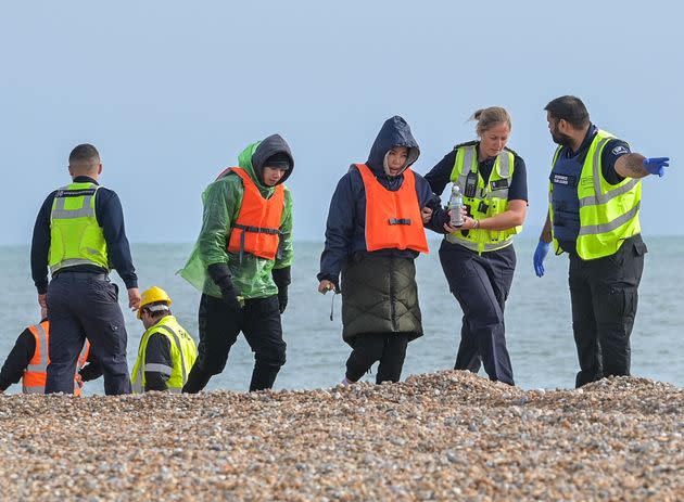 Migrants being helped ashore from a packed lifeboat by the border force and police officers are taken to Dungeness beach in Kent (Photo: Anadolu Agency via Getty Images)